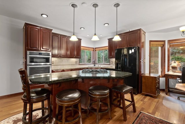 kitchen featuring light wood-style floors, a breakfast bar area, stainless steel appliances, and backsplash