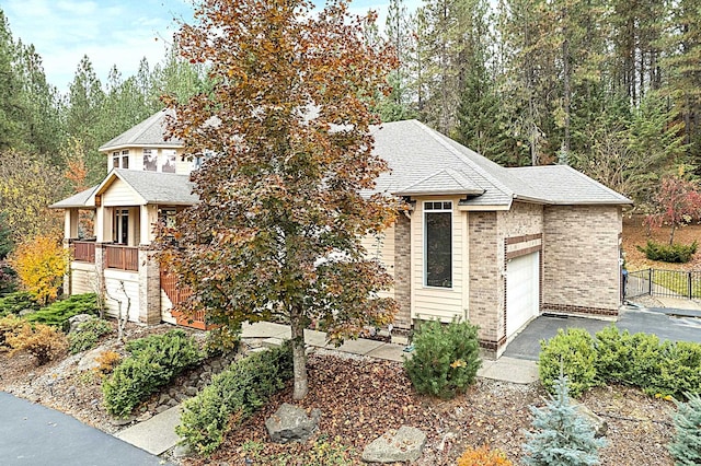 view of front of property featuring a garage, a shingled roof, aphalt driveway, fence, and brick siding