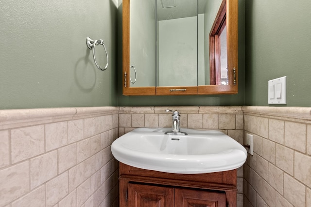 bathroom with wainscoting, vanity, and tile walls