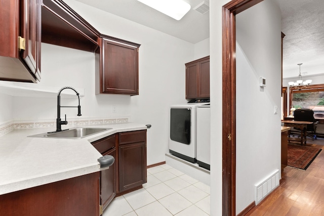 kitchen featuring an inviting chandelier, visible vents, a sink, and independent washer and dryer