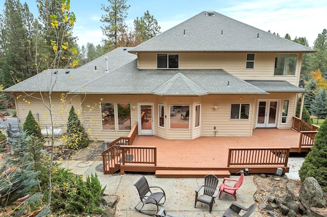 back of house with a wooden deck, a fire pit, a shingled roof, and french doors