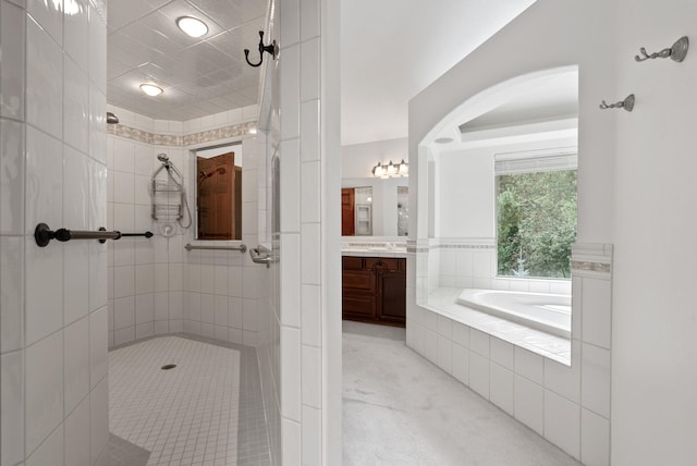 bathroom featuring a garden tub, a tile shower, and vanity