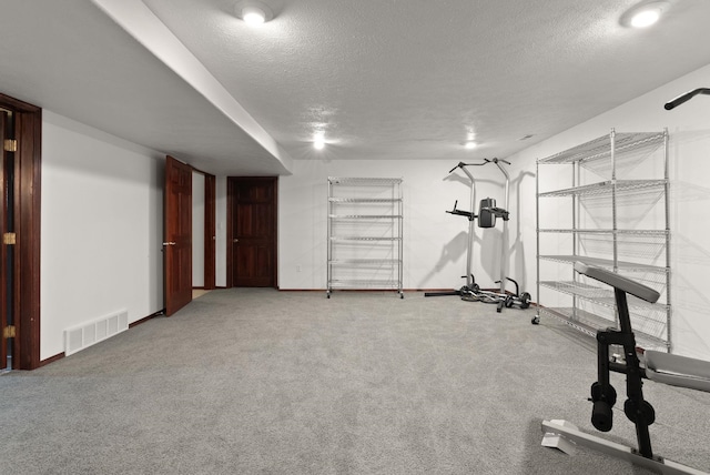 exercise area featuring carpet floors, baseboards, visible vents, and a textured ceiling