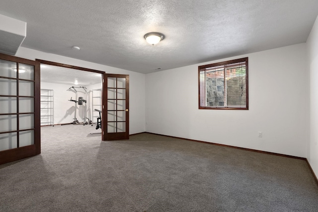 empty room with carpet floors, baseboards, a textured ceiling, and french doors