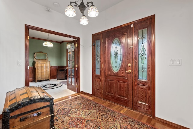 foyer entrance featuring a wainscoted wall, an inviting chandelier, and wood finished floors