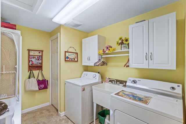 clothes washing area with a sink, washing machine and dryer, cabinet space, and baseboards