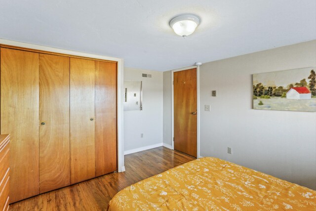 unfurnished bedroom featuring baseboards, a closet, visible vents, and wood finished floors