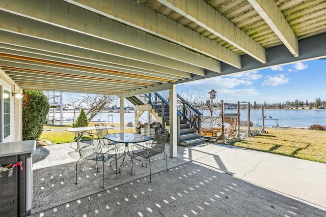 view of patio featuring a water view, stairway, and outdoor dining space