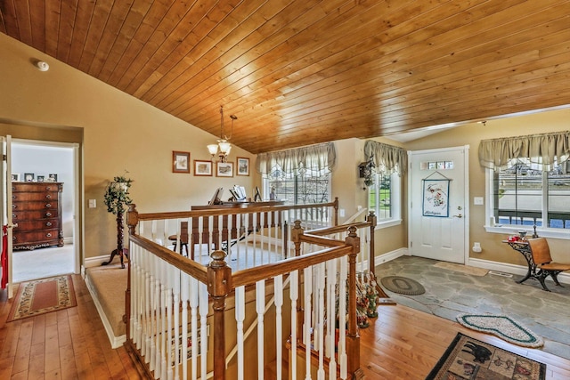 hall featuring lofted ceiling, hardwood / wood-style floors, and an upstairs landing