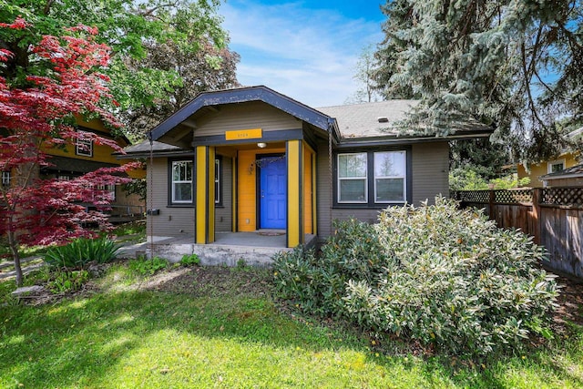 bungalow-style house with a front lawn and fence