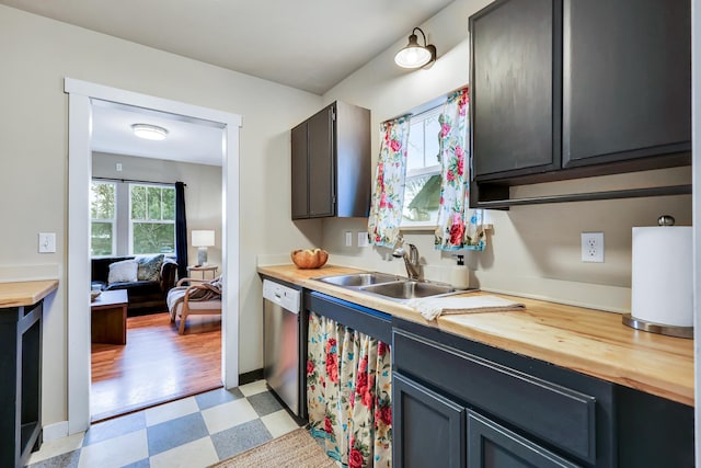 kitchen featuring a sink, baseboards, wooden counters, dishwasher, and light floors