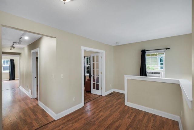 unfurnished room with cooling unit, dark wood-style flooring, rail lighting, and baseboards