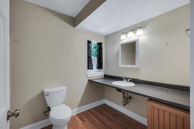 bathroom with baseboards, a sink, toilet, and wood finished floors