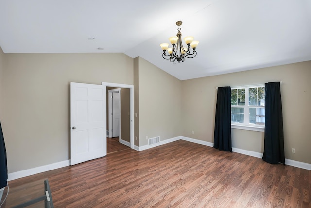 spare room with baseboards, visible vents, lofted ceiling, wood finished floors, and an inviting chandelier