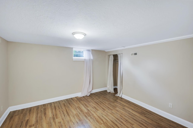 interior space with a textured ceiling, visible vents, light wood-style flooring, and baseboards