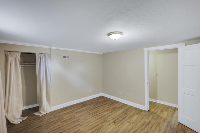 unfurnished bedroom with wood finished floors, visible vents, and baseboards