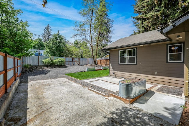 view of yard with gravel driveway, a fenced backyard, and a patio