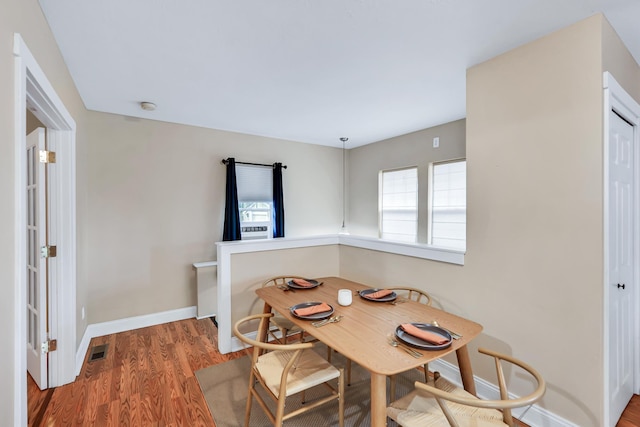 dining area featuring wood finished floors, visible vents, and baseboards