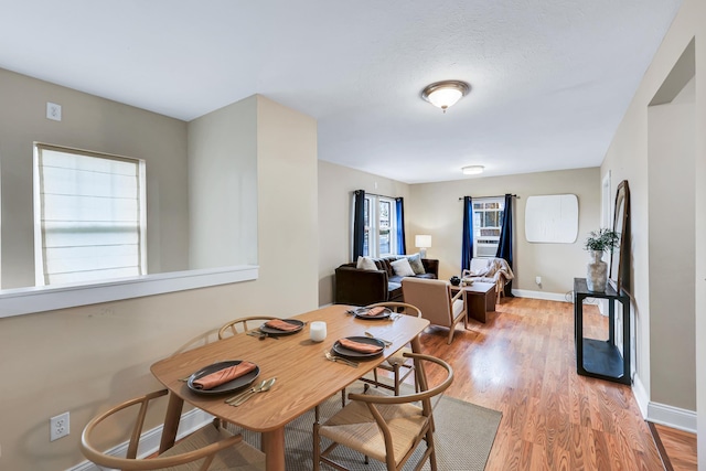 dining space with a wealth of natural light, light wood-style flooring, and baseboards