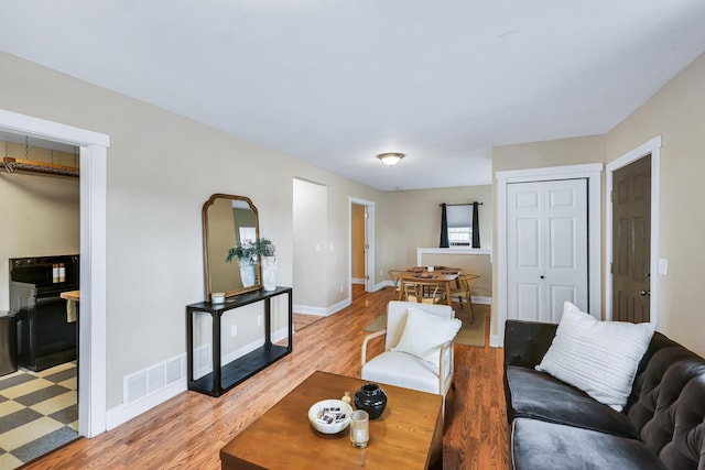 living area with visible vents, light wood-style flooring, and baseboards