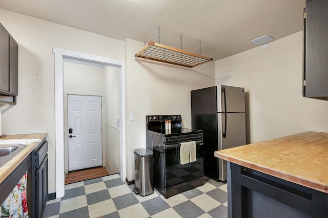 kitchen featuring light floors, black electric range oven, and freestanding refrigerator