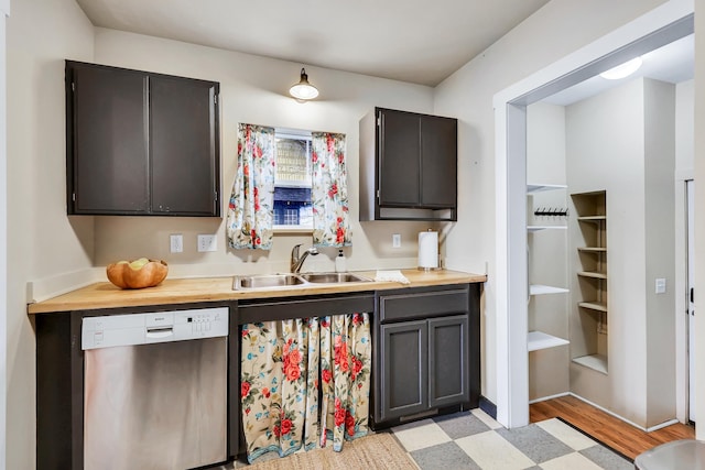 kitchen featuring light floors, a sink, wood counters, and stainless steel dishwasher