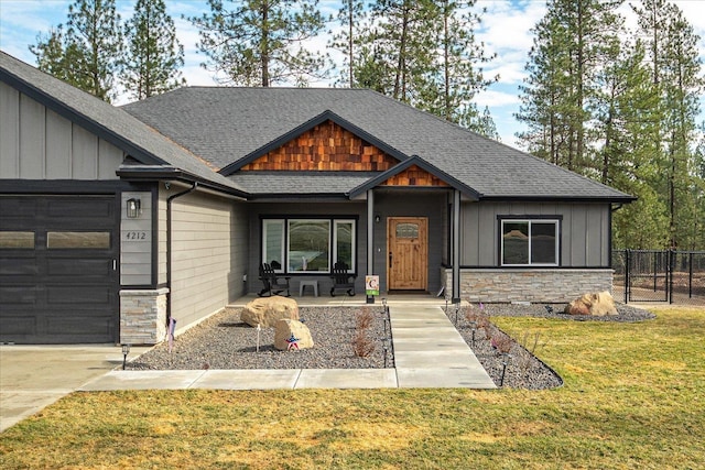 view of front of house with a garage, stone siding, fence, and board and batten siding