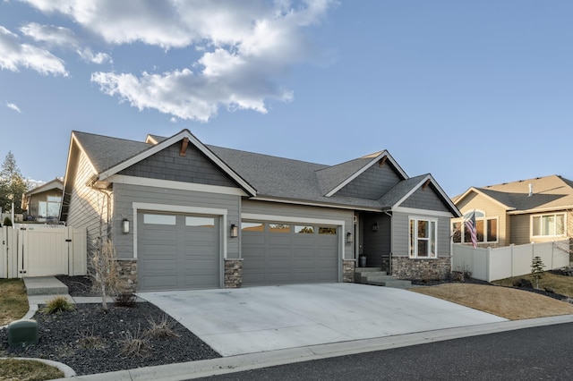 craftsman-style house featuring a garage, a gate, fence, and stone siding