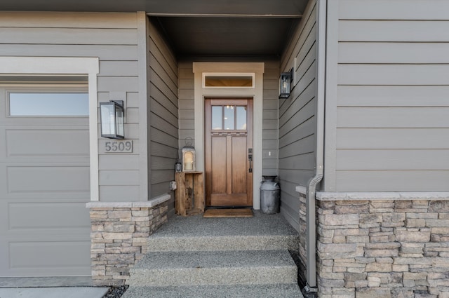 property entrance featuring a garage and stone siding