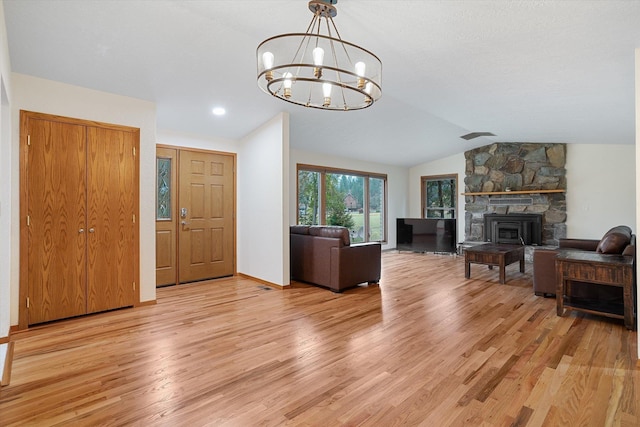 living area featuring an inviting chandelier, light wood-style flooring, baseboards, and vaulted ceiling