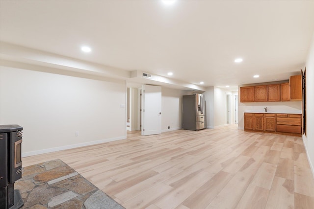 unfurnished living room featuring a wood stove, light wood finished floors, visible vents, and recessed lighting