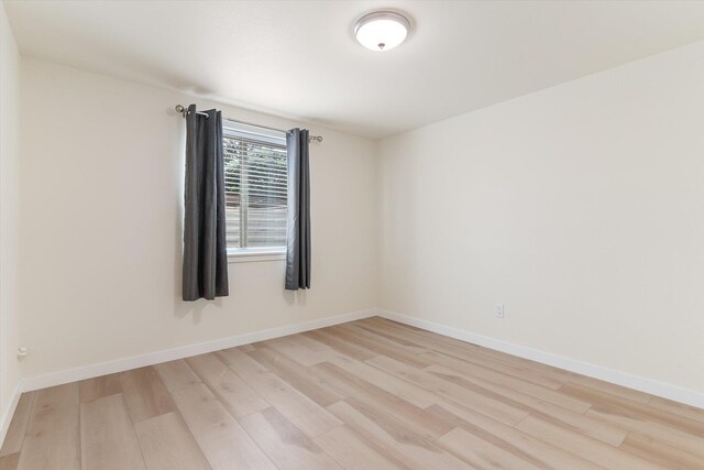 unfurnished room with light wood-style flooring and baseboards