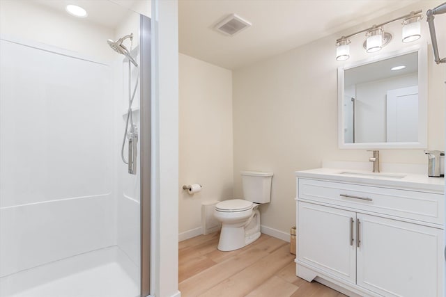 full bathroom featuring toilet, wood finished floors, vanity, visible vents, and a shower stall