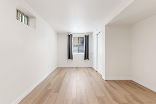 empty room with light wood finished floors, visible vents, and baseboards