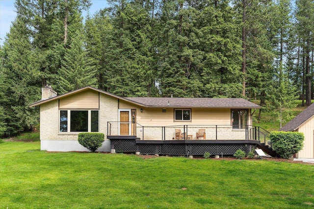 back of house featuring brick siding, a lawn, a chimney, and a wooden deck