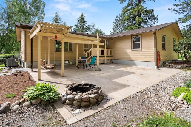 rear view of property with a fire pit, cooling unit, and a patio