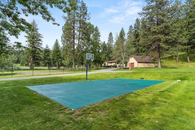 view of basketball court with community basketball court, fence, and a lawn