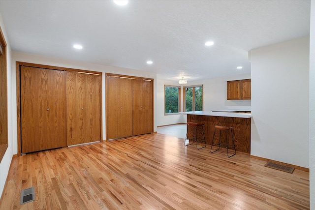 interior space featuring a peninsula, a breakfast bar, light wood-style flooring, and visible vents