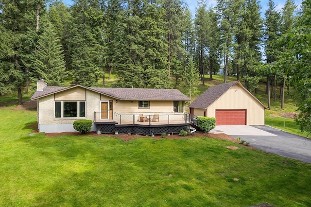 view of front of property featuring an outbuilding, brick siding, a detached garage, a front yard, and a deck