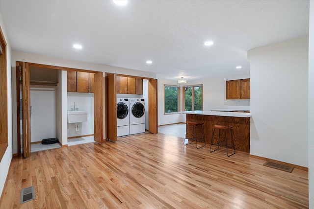 kitchen featuring a peninsula, separate washer and dryer, brown cabinetry, and visible vents