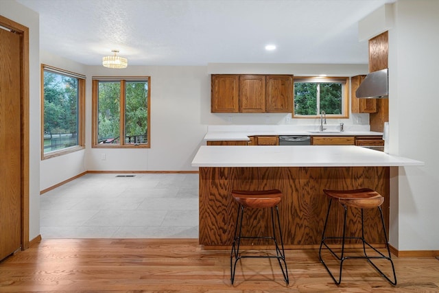 kitchen with a wealth of natural light, brown cabinets, a sink, and a kitchen breakfast bar