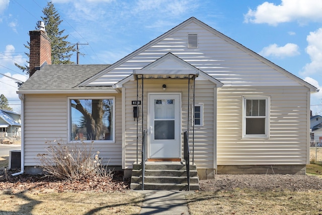 bungalow-style house featuring a shingled roof, entry steps, and a chimney