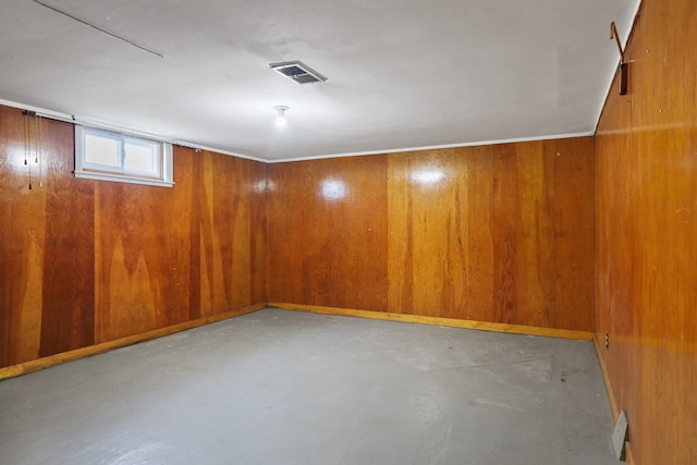 empty room with wooden walls, visible vents, and finished concrete floors