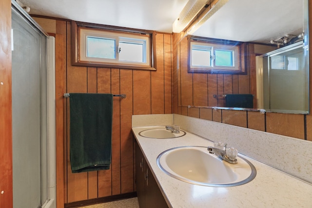 full bath featuring a stall shower, a sink, and wood walls