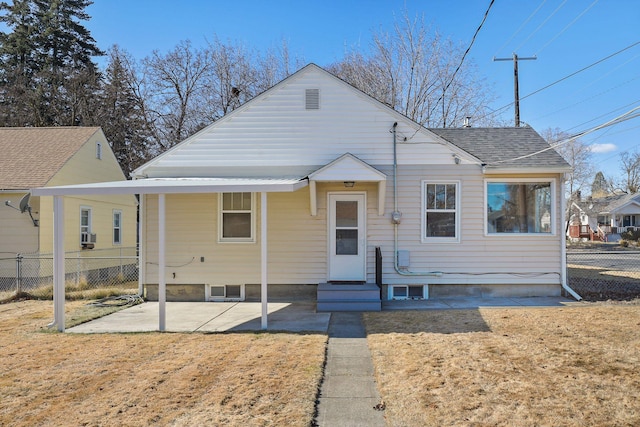 bungalow-style home with a shingled roof, a front yard, a patio area, and fence