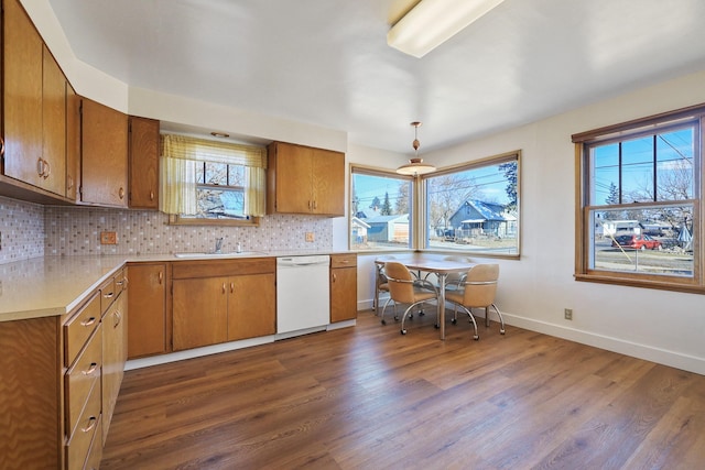 kitchen with decorative backsplash, brown cabinetry, white dishwasher, light countertops, and a sink