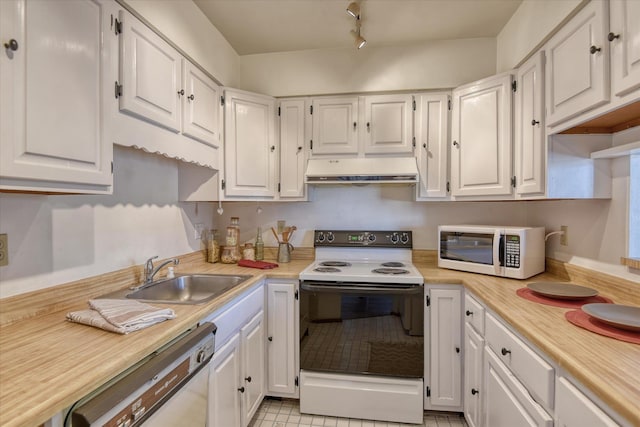 kitchen featuring under cabinet range hood, white cabinetry, white appliances, and a sink