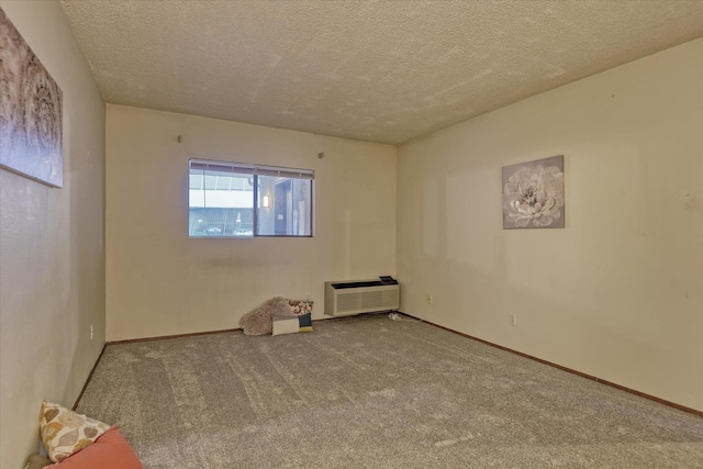 unfurnished room with carpet floors, a wall mounted air conditioner, a textured ceiling, and baseboards