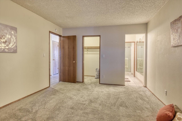 unfurnished bedroom with a textured ceiling, a closet, carpet flooring, and a walk in closet