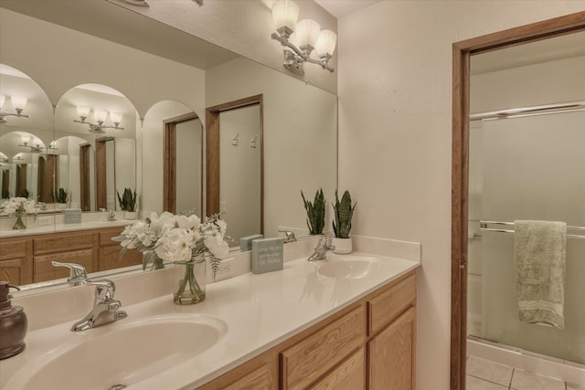 bathroom with a stall shower, a chandelier, a sink, and tile patterned floors